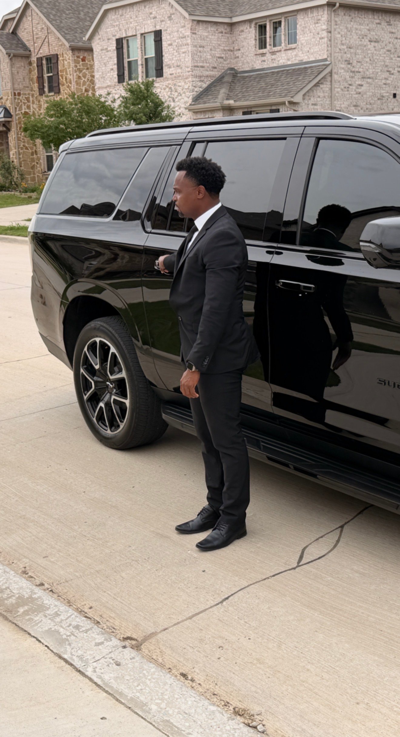 NoirRide chauffeur standing beside the black Suburban